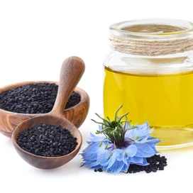 Schwarzkümmelöl mit Samen und Blüten